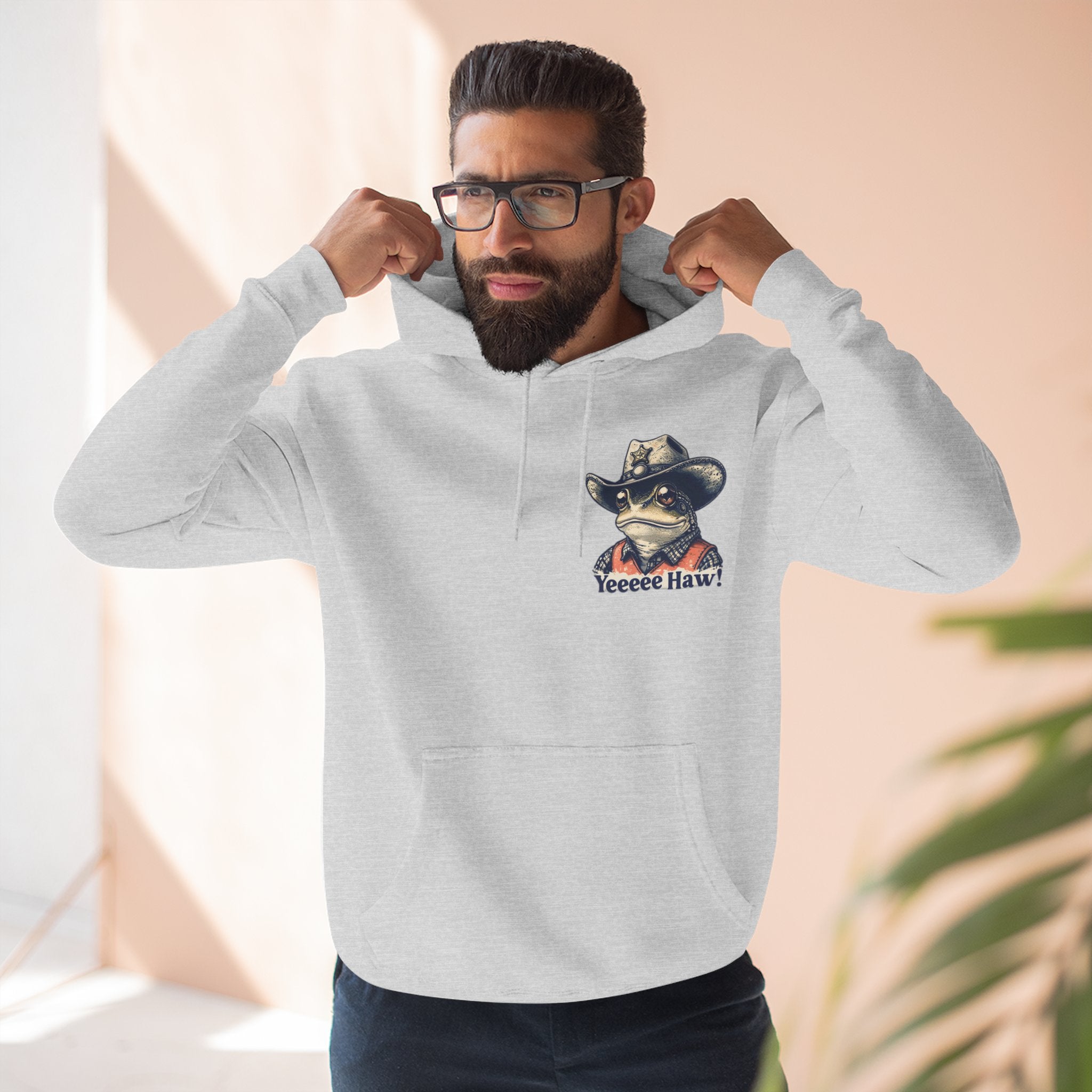 Man wearing a gray cowboy hoodie with a graphic design on a neutral background