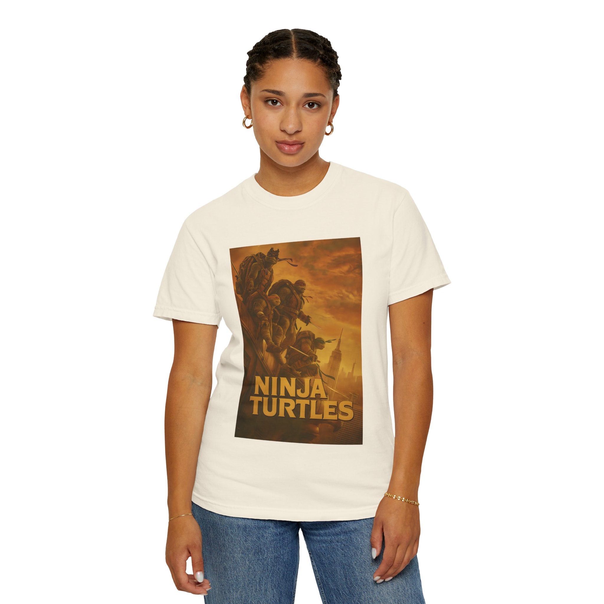 Person wearing a ivory t-shirt with 'Ninja Turtles' graphic design on a plain background
