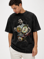 Model wearing an oversized black snow-washed Manny Pacquiao graphic T-shirt featuring a boxing portrait, gold championship belts and red signature artwork.