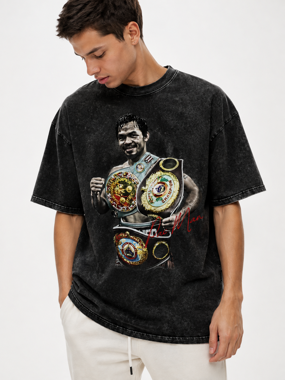 Model wearing an oversized black snow-washed Manny Pacquiao graphic T-shirt featuring a boxing portrait, gold championship belts and red signature artwork.