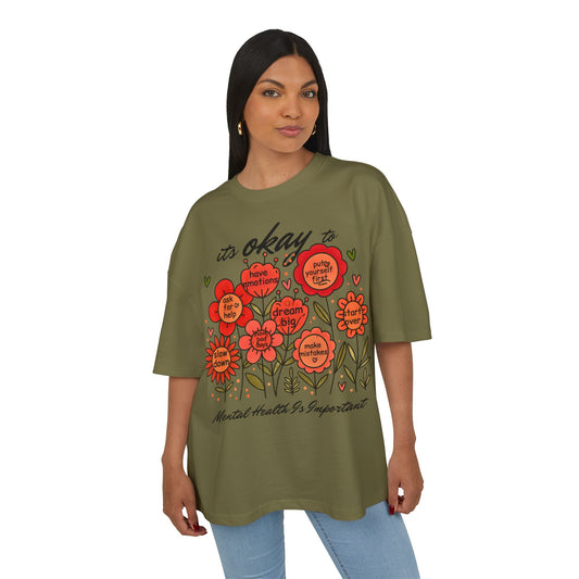 Woman wearing an olive green t-shirt with floral designs and text on a white background