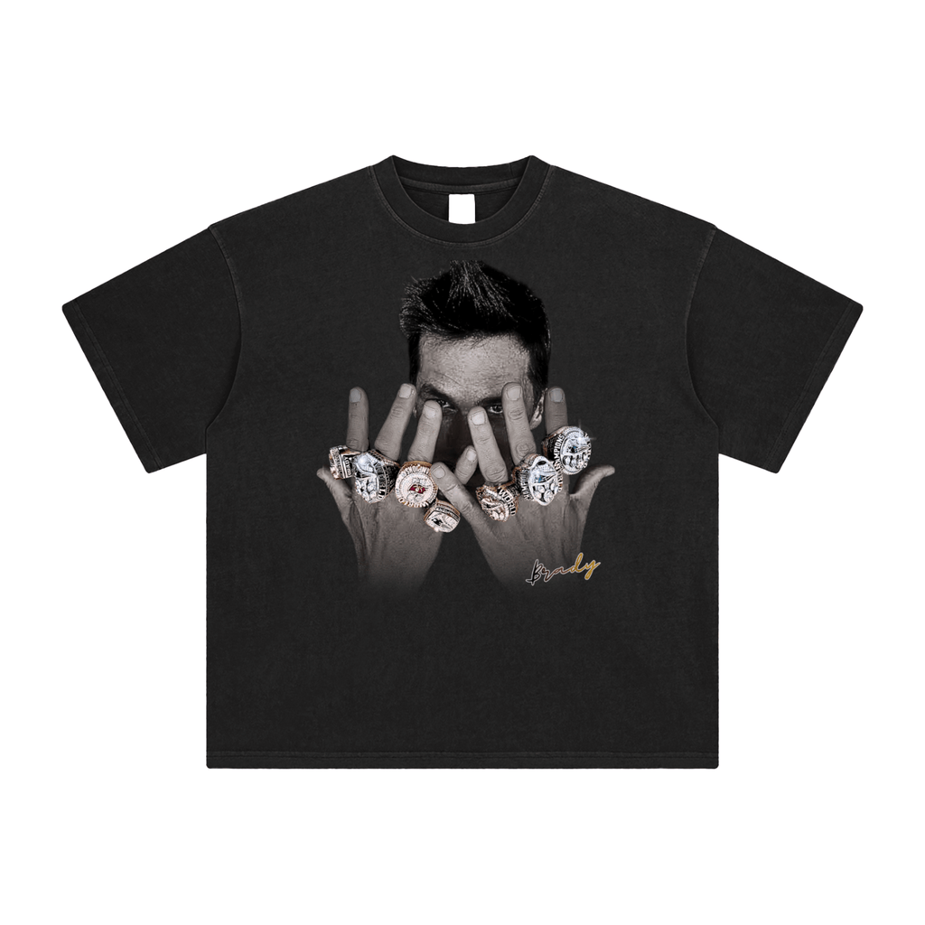 Tom Brady with his championship rings on a black tshirt in a white background