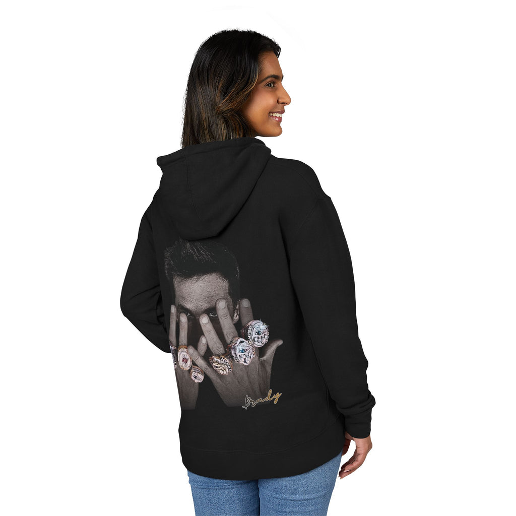 woman wearing a black hoodie with a graphic design of tom brady on the back, standing against a white background